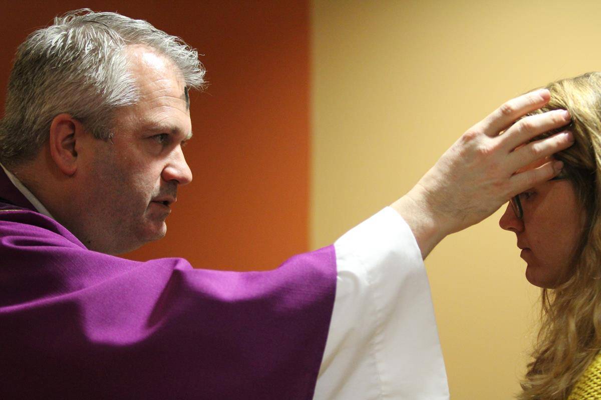 CHARLOTTE —Father Patrick Winslow, vicar general and chancellor, distributes ashes at the Pastoral Center in Charlotte on Ash Wednesday. (Photos by SueAnn Howell) 