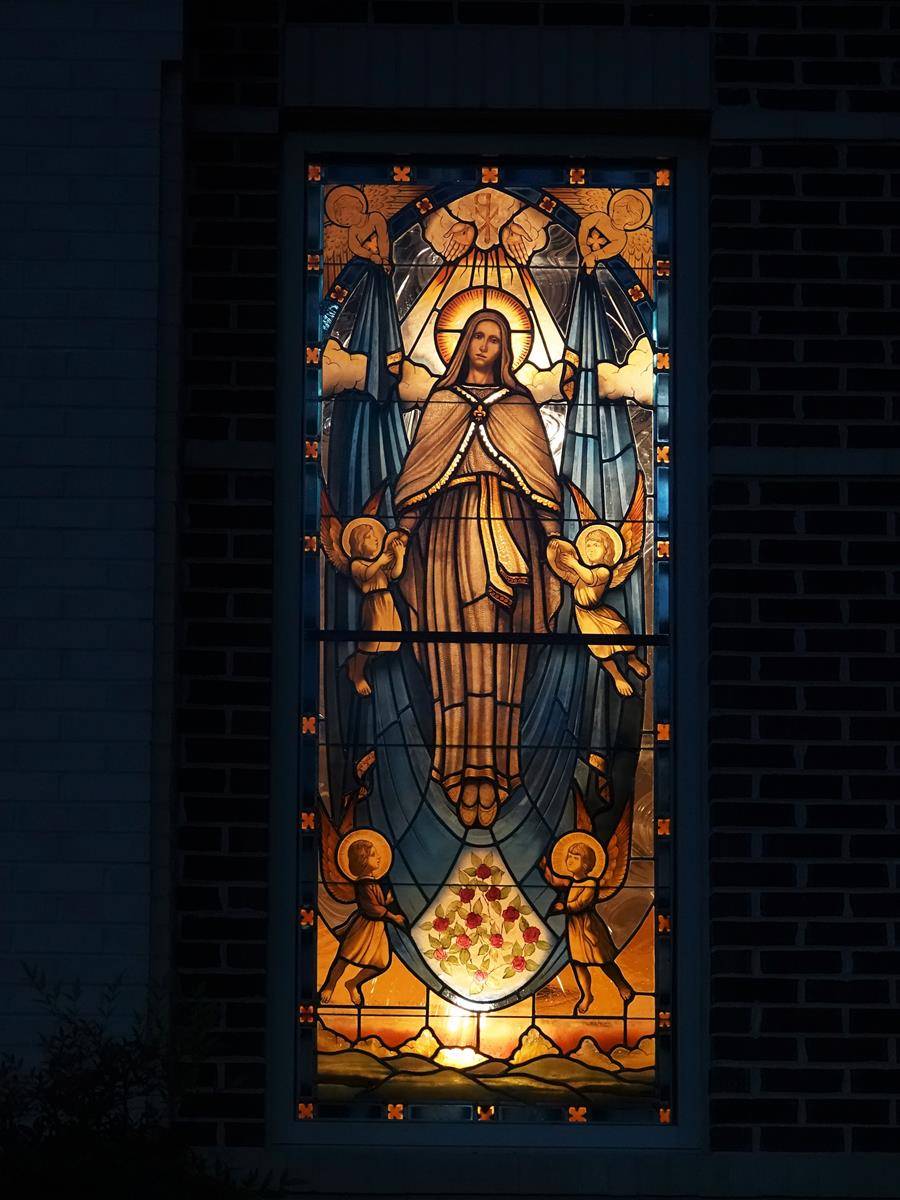 St. Mark stained glass Assumption window lit up at night.